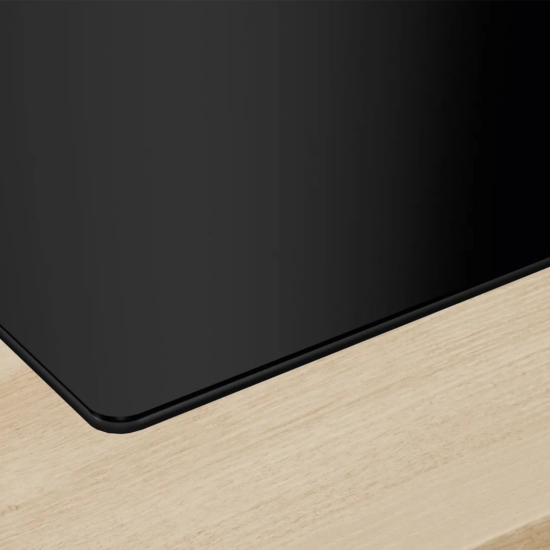 Close up of a black cooktop with integrated ventilation on a light wooden countertop