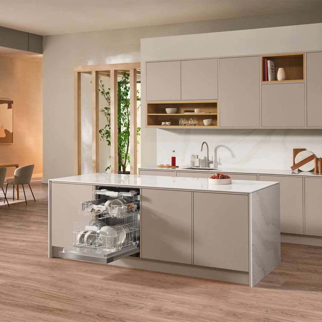 A Miele dishwasher with racks pulled out in a modern kitchen island