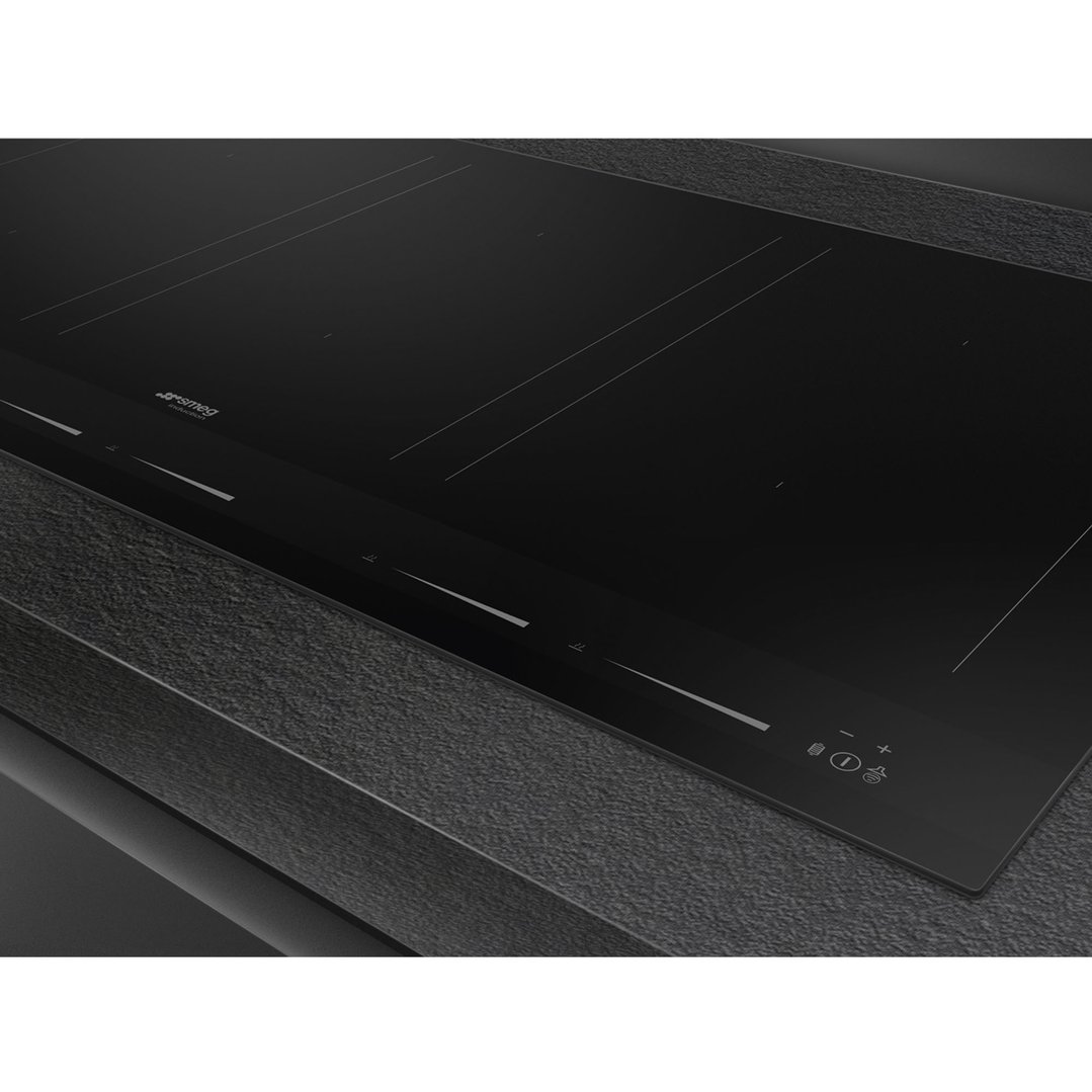 Close up of a black induction cooktop built into a dark textured countertop