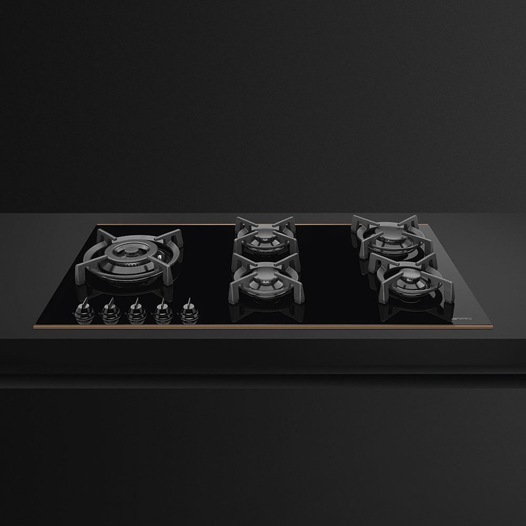 Black gas cooktop with five burners and controls on a dark countertop