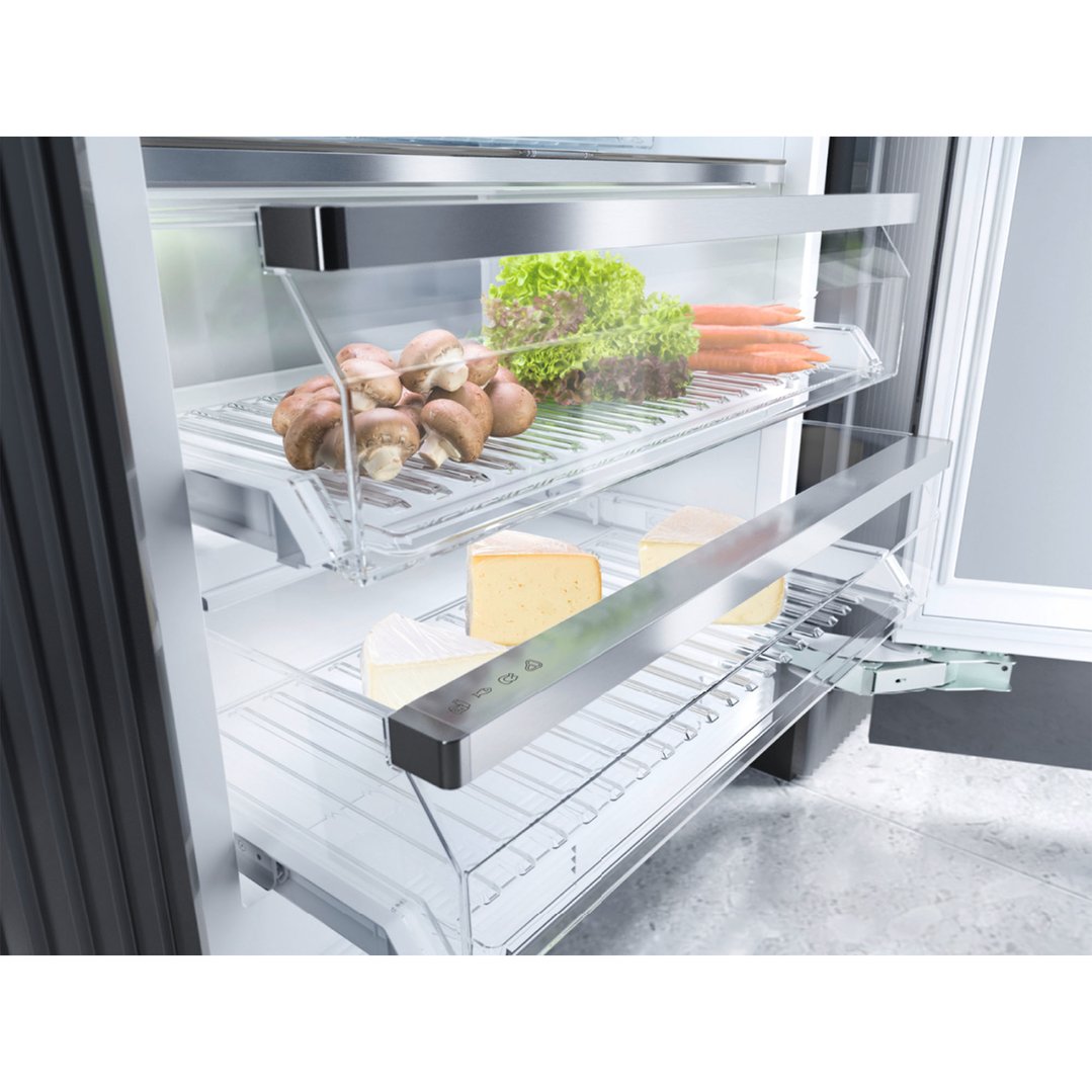 Open integrated fridge with mushrooms, lettuce, carrots, and cheese on shelves