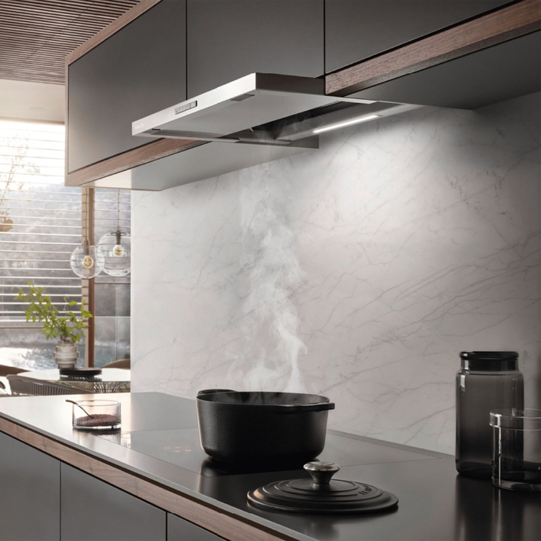 A Miele rangehood above a cooktop with a pot steaming in a modern kitchen