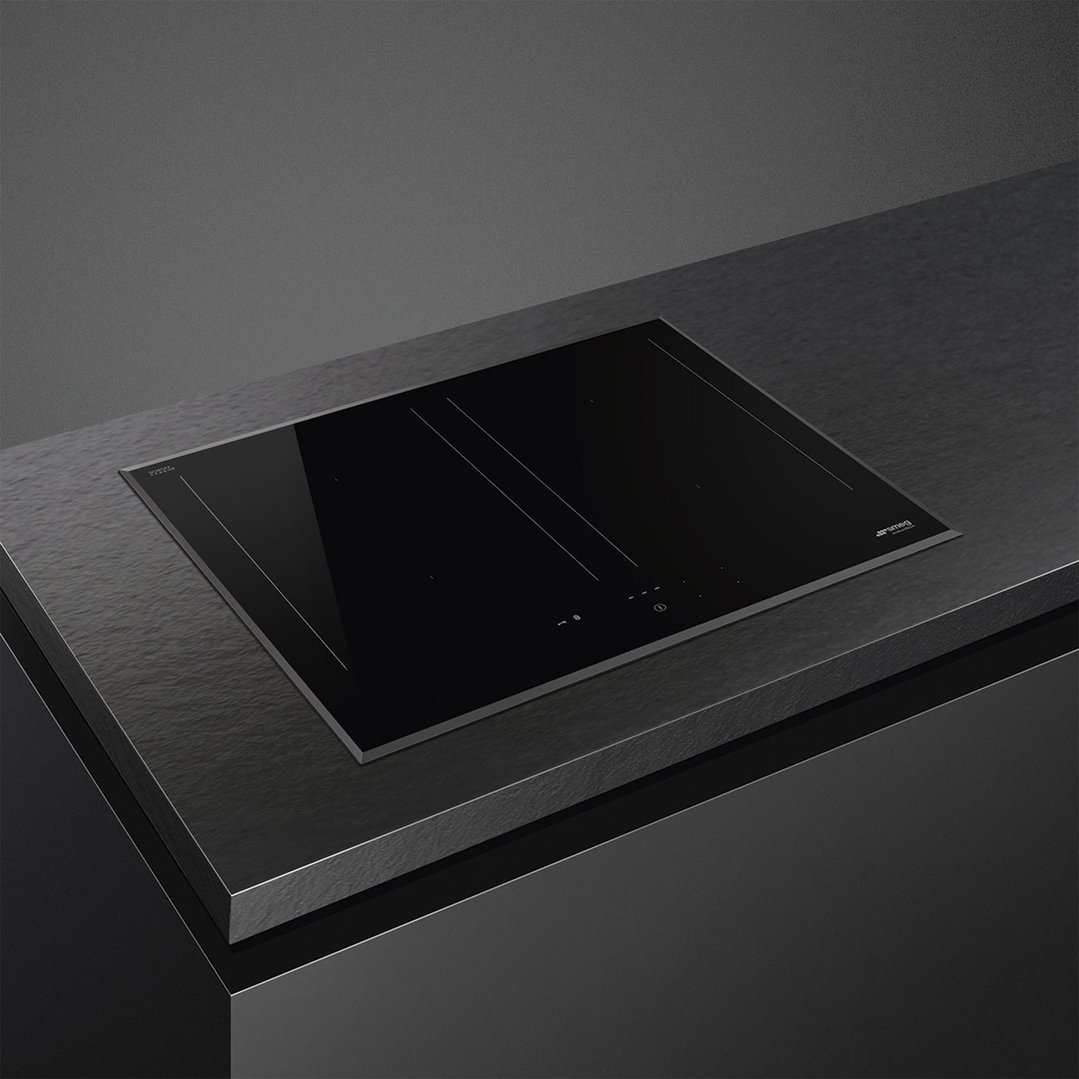 Black induction cooktop built into a dark countertop in a modern kitchen