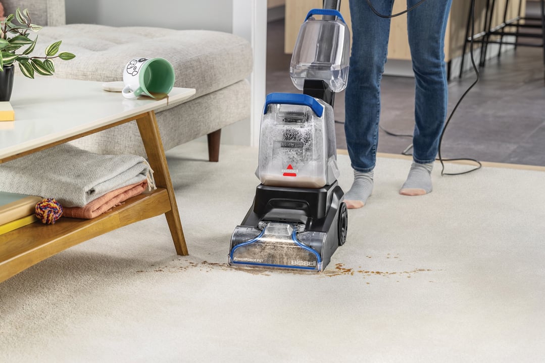 Person cleaning a spill on a carpet with a BISSELL PowerForce Pet carpet cleaner