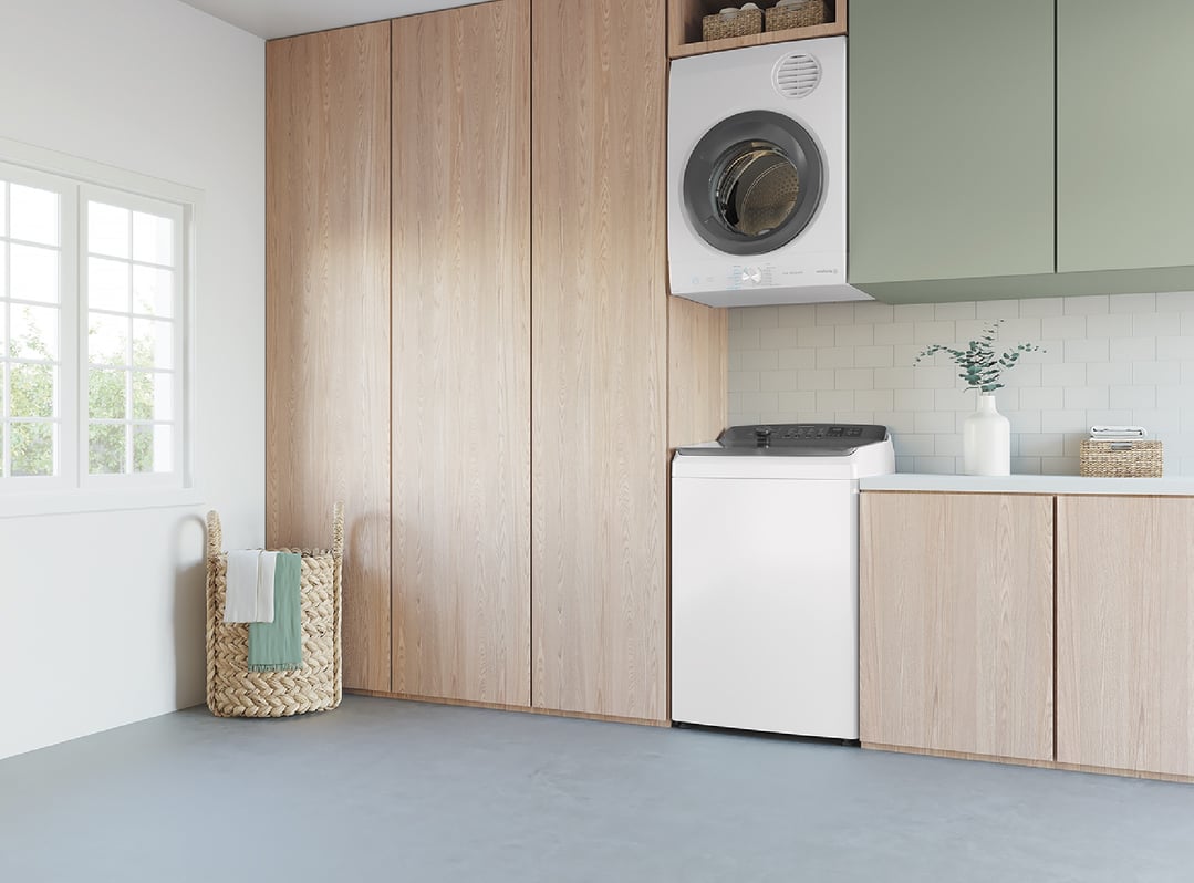 Top load washing machine and dryer in a modern laundry room with wooden cabinets