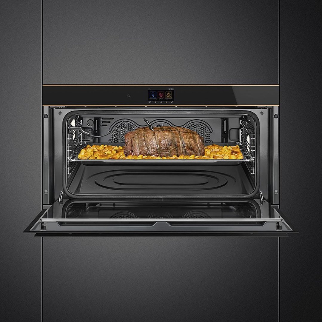 Built-in oven with door open, cooking a roast and potatoes