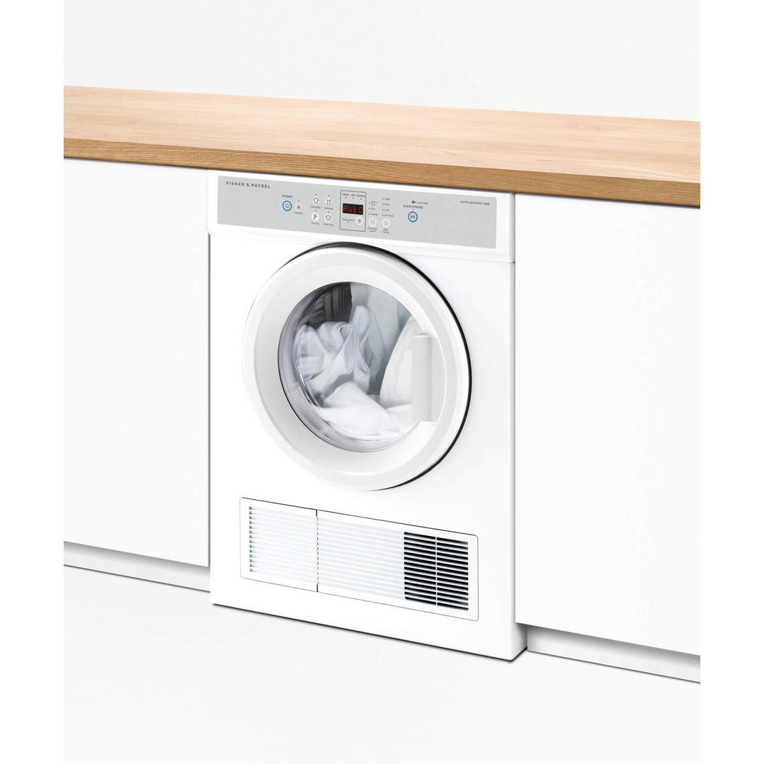 White Fisher & Paykel dryer built into a white cabinet under a wooden countertop