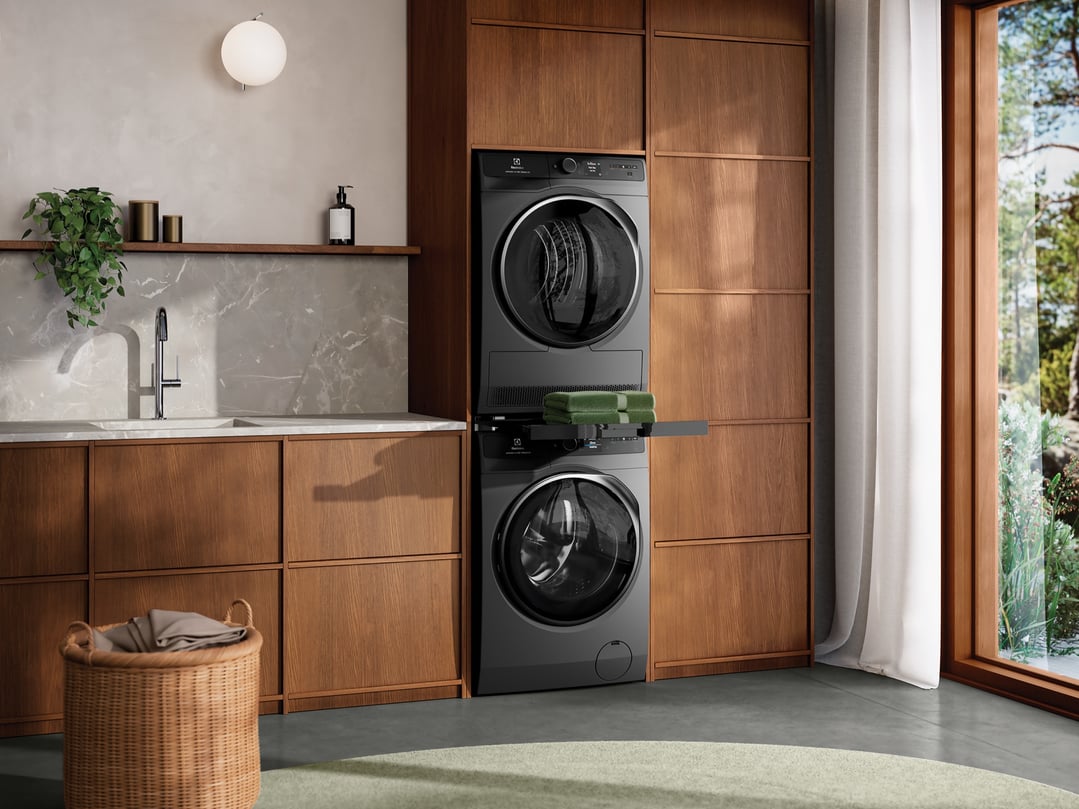 Two dark onyx dryers stacked in a modern laundry room with wooden cabinetry