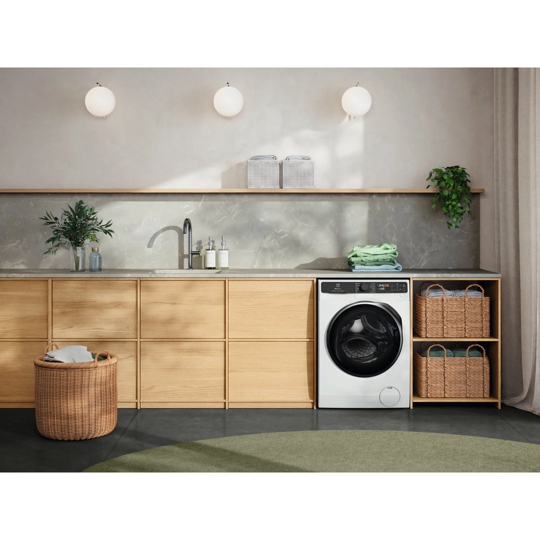 White washer dryer combo in a modern laundry room with wooden cabinets