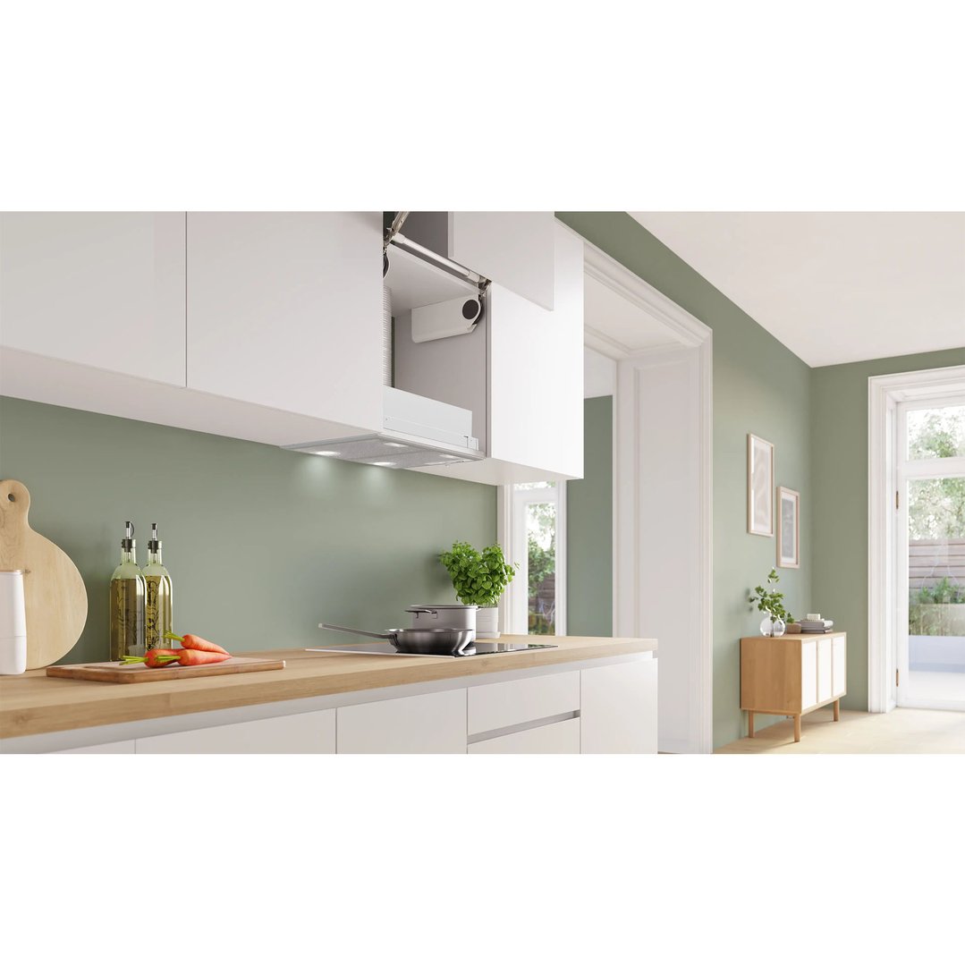 Integrated rangehood in a modern kitchen with light green walls and wooden countertops