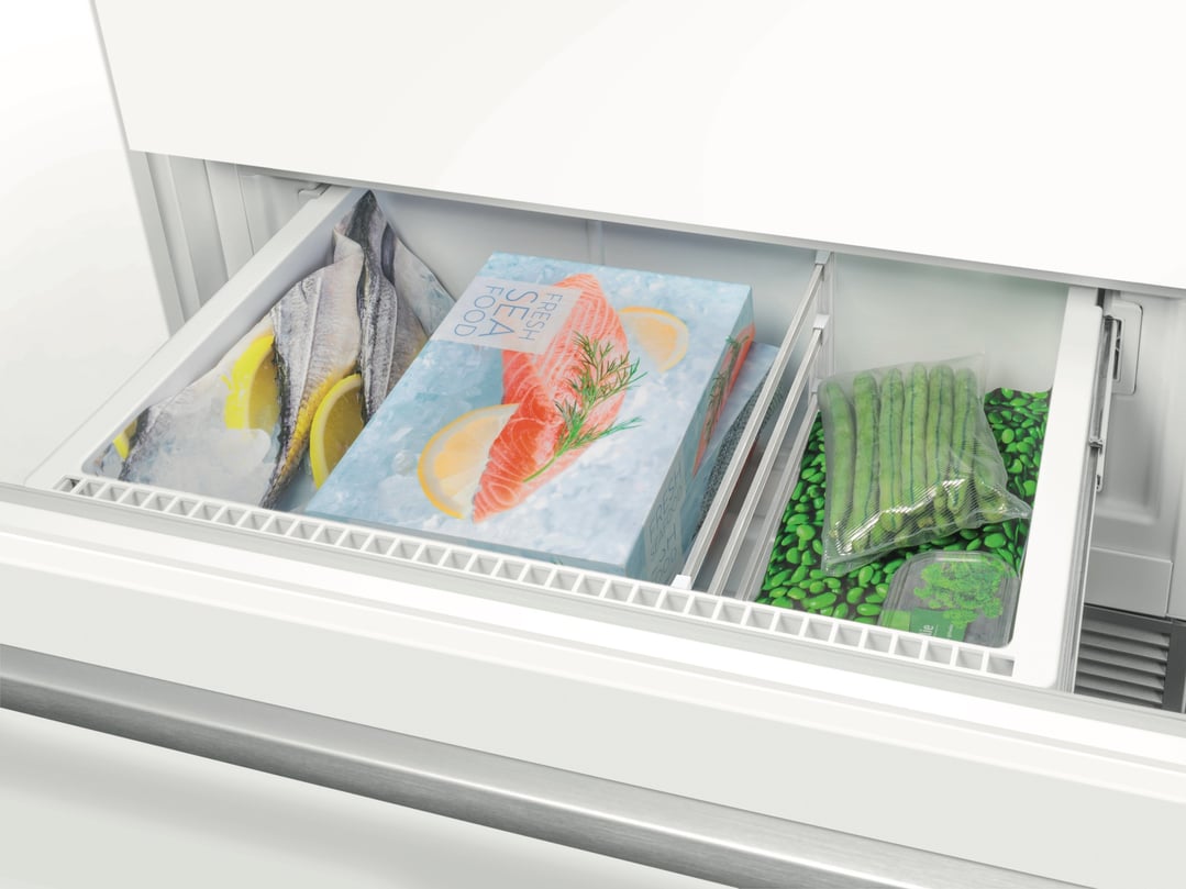 Open freezer drawer of a fridge with frozen food items inside