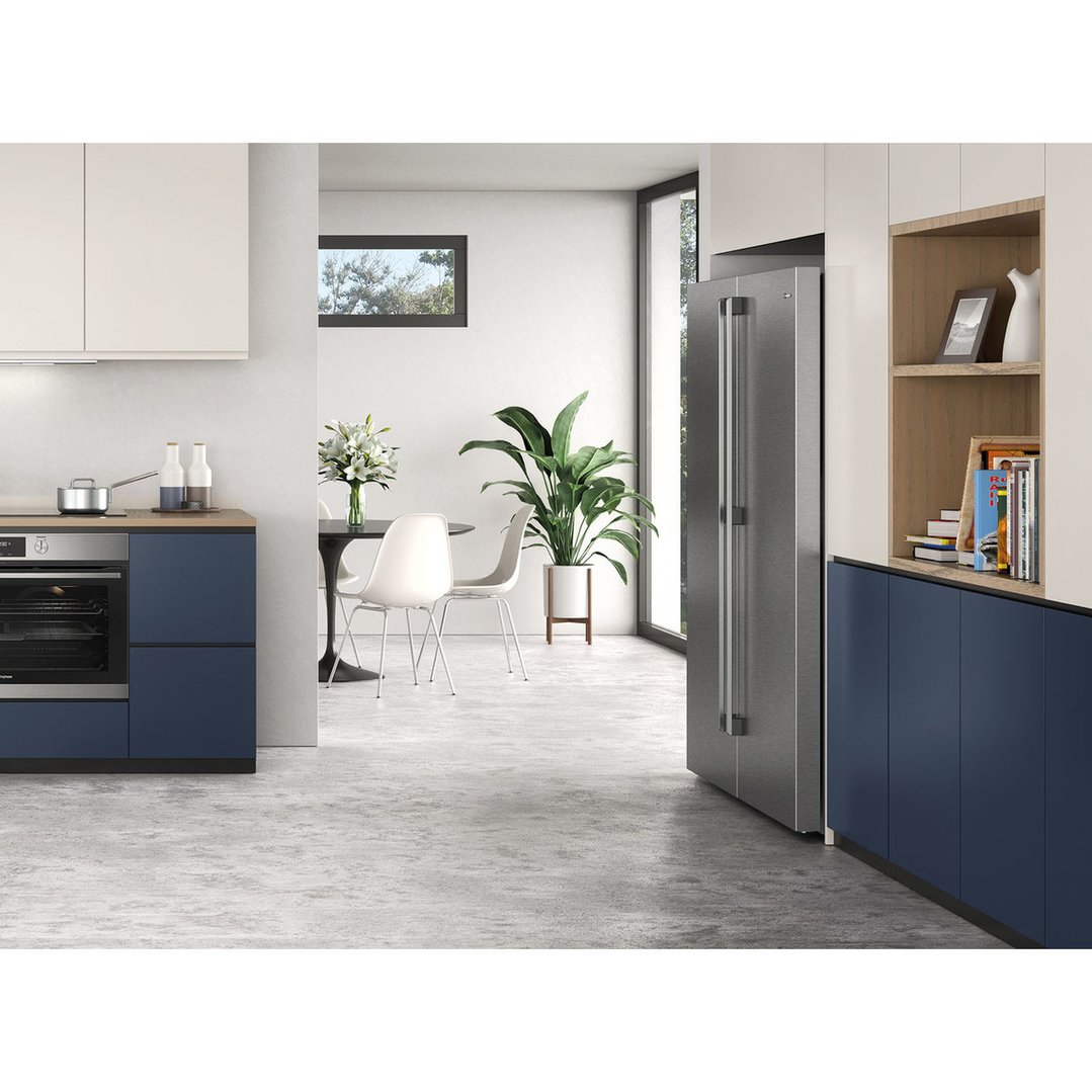 Stainless steel single door fridge in a modern kitchen with blue cabinets and dining area