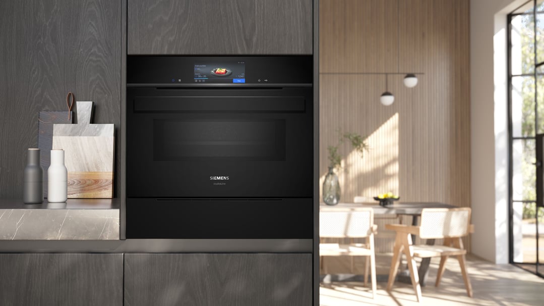 Built-in steam drawer in a dark wood kitchen with a dining area