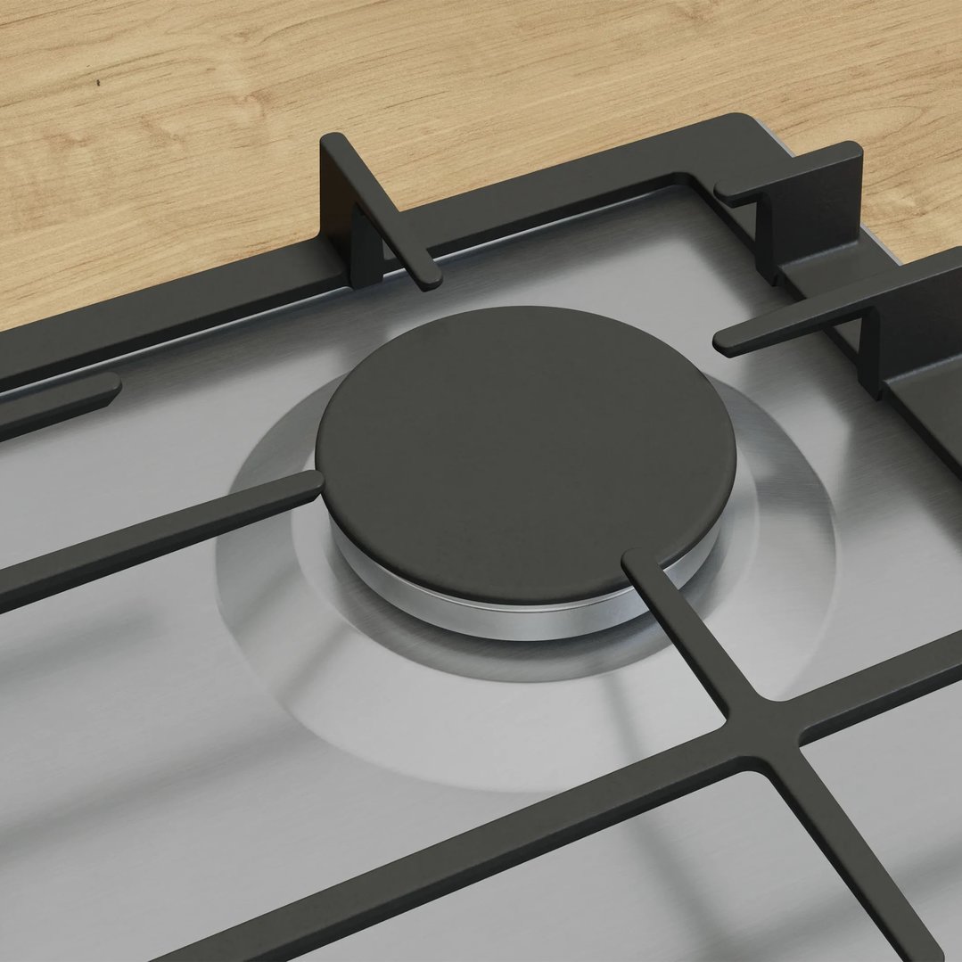 Close up of a gas cooktop burner and grates on a wooden countertop