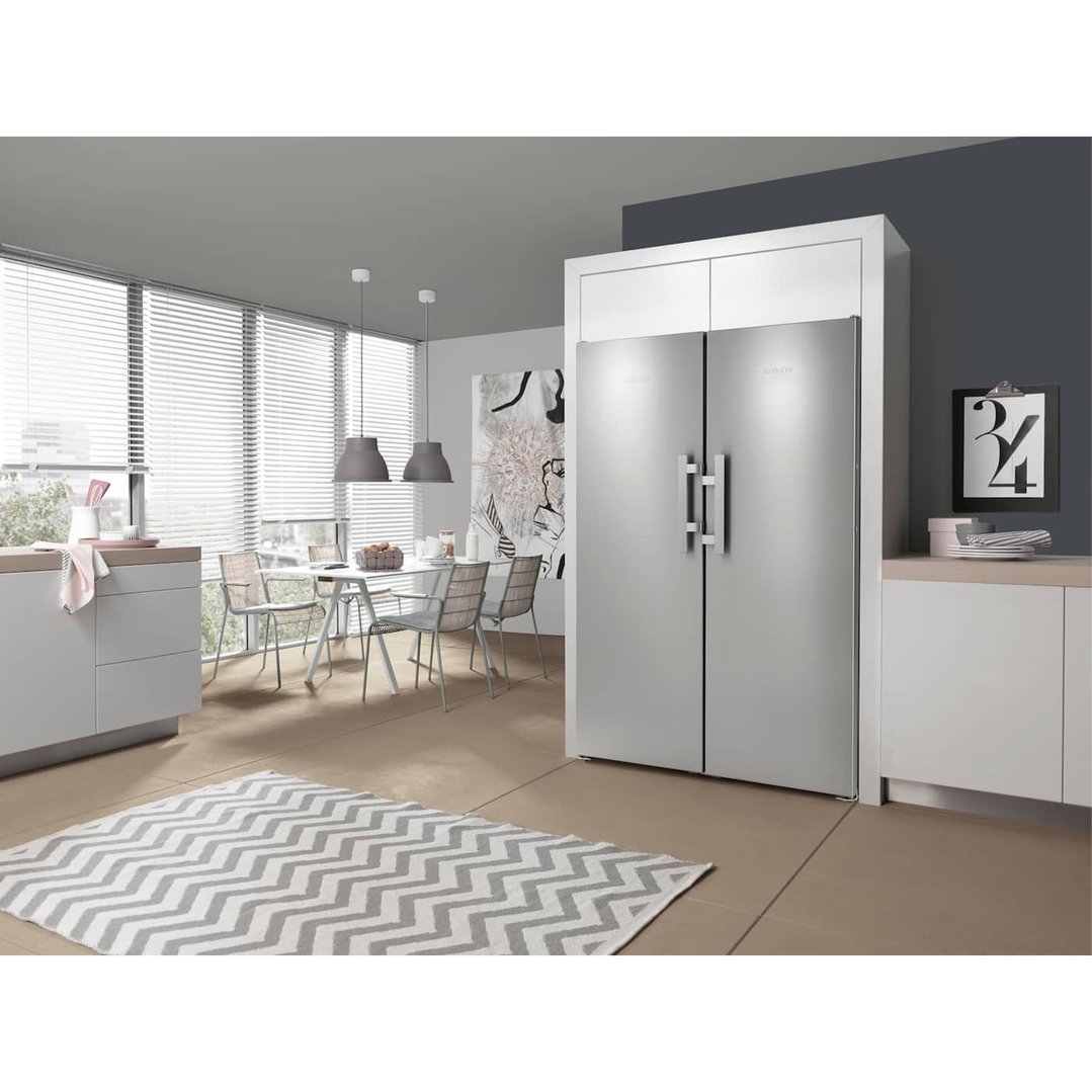 Stainless steel side-by-side refrigerator in a modern kitchen with dining area