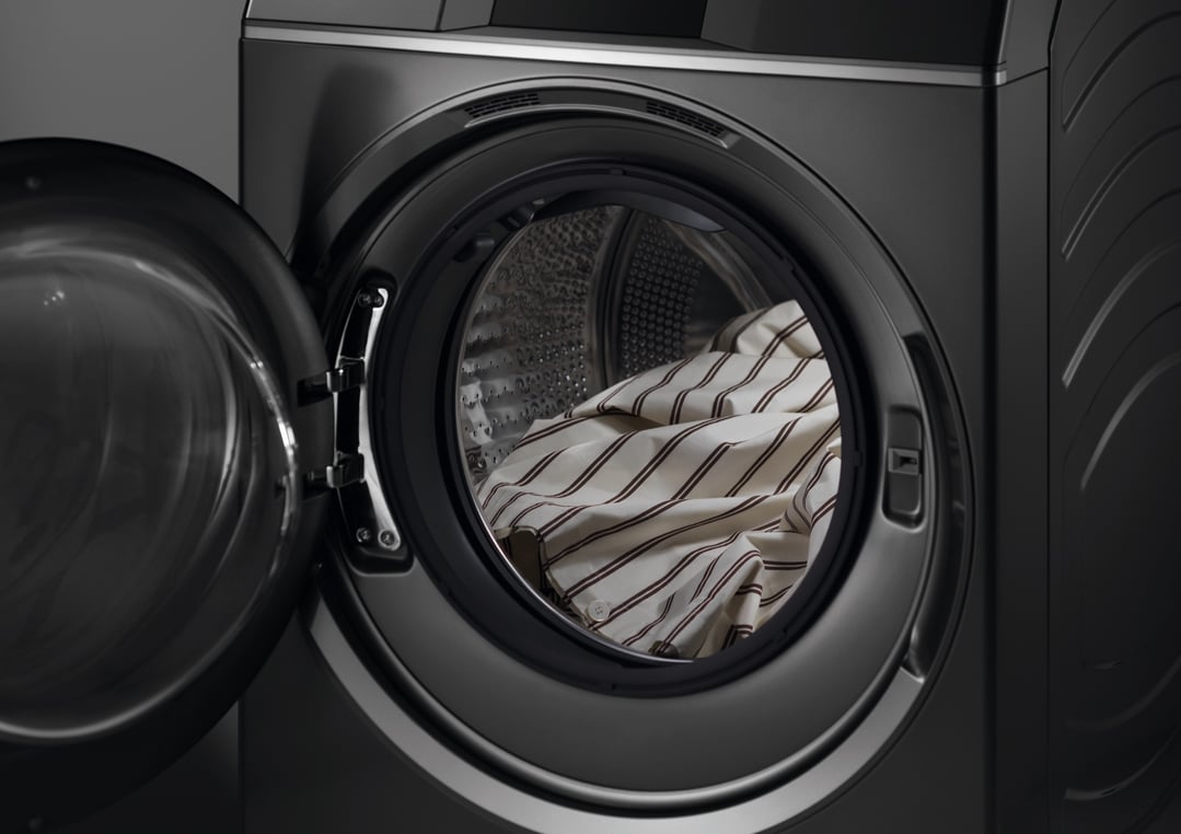 Close-up of a dark washer dryer combo with the door open and laundry inside