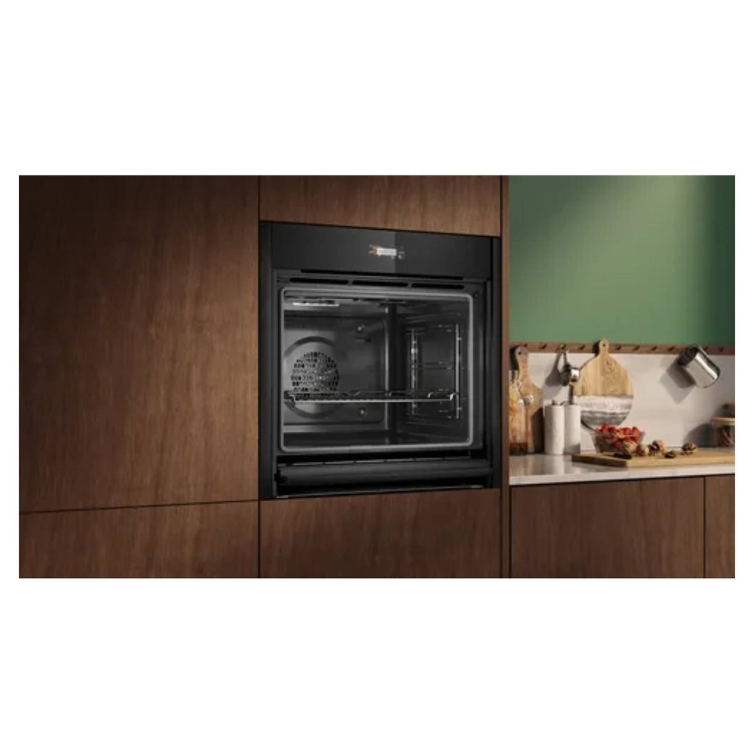 Built-in oven in a modern kitchen with wooden cabinetry and green wall