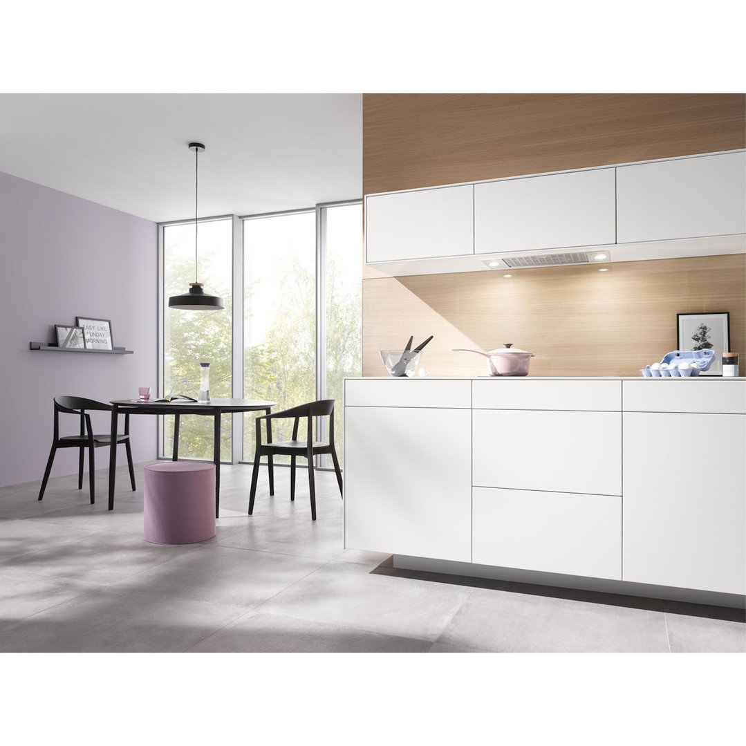 A modern kitchen and dining area with a built-in rangehood and white cabinetry