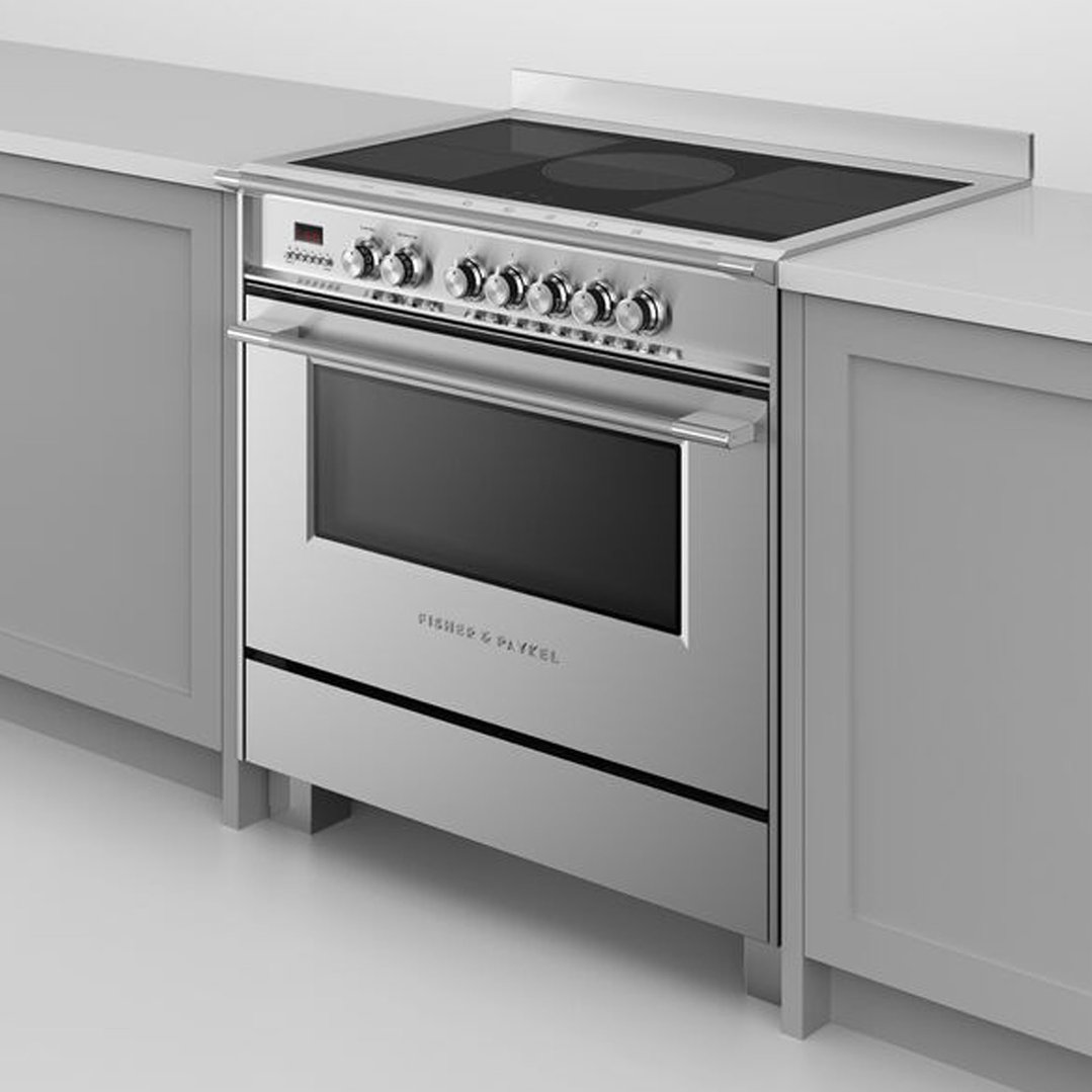 Stainless steel induction cooker with an oven built into a light grey kitchen cabinet.