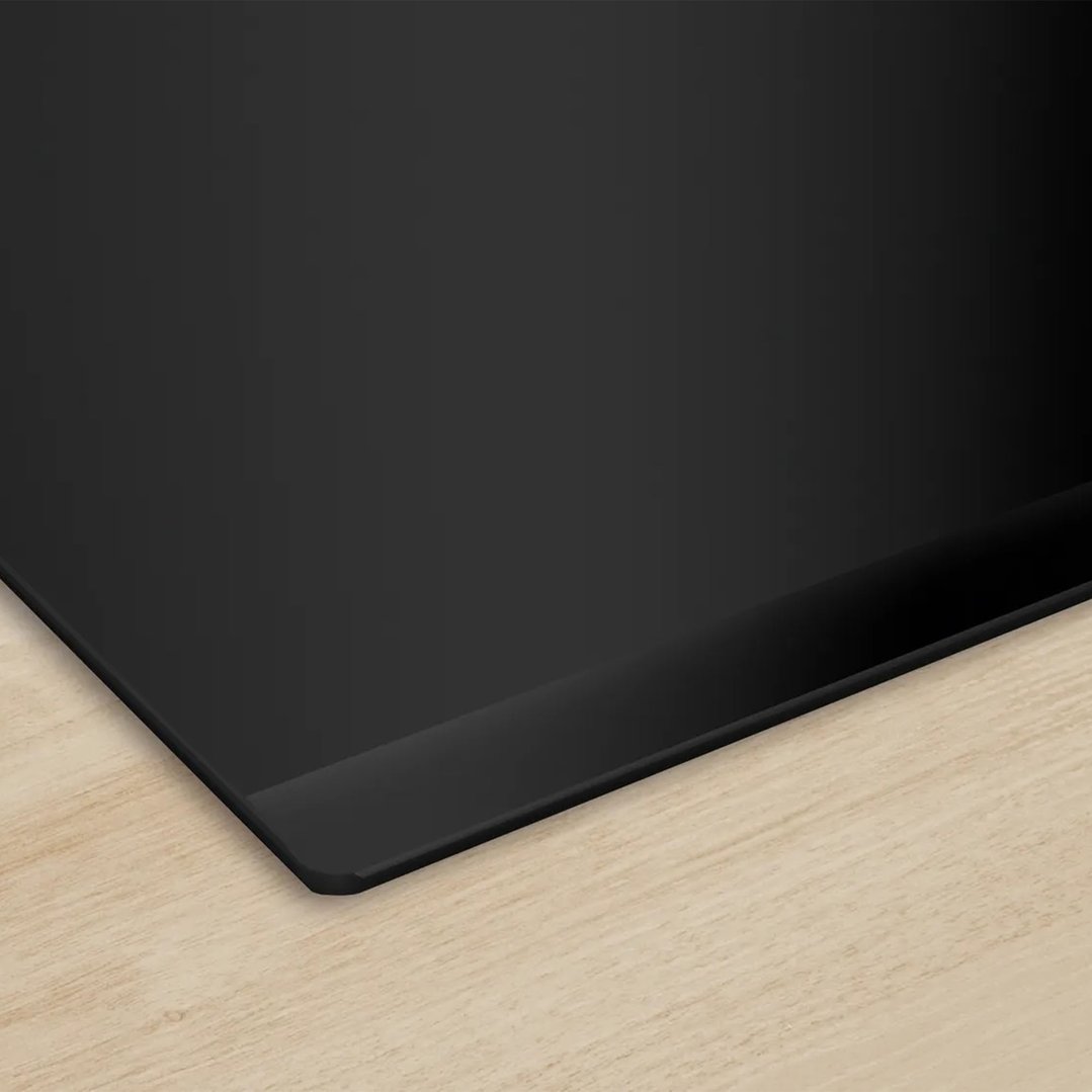 Black induction cooktop on a light wood countertop, close-up, angled view