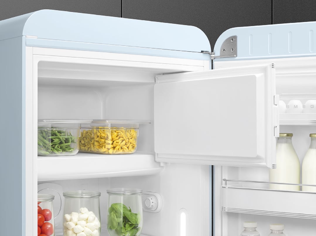 Open pastel blue retro refrigerator filled with food items and drinks