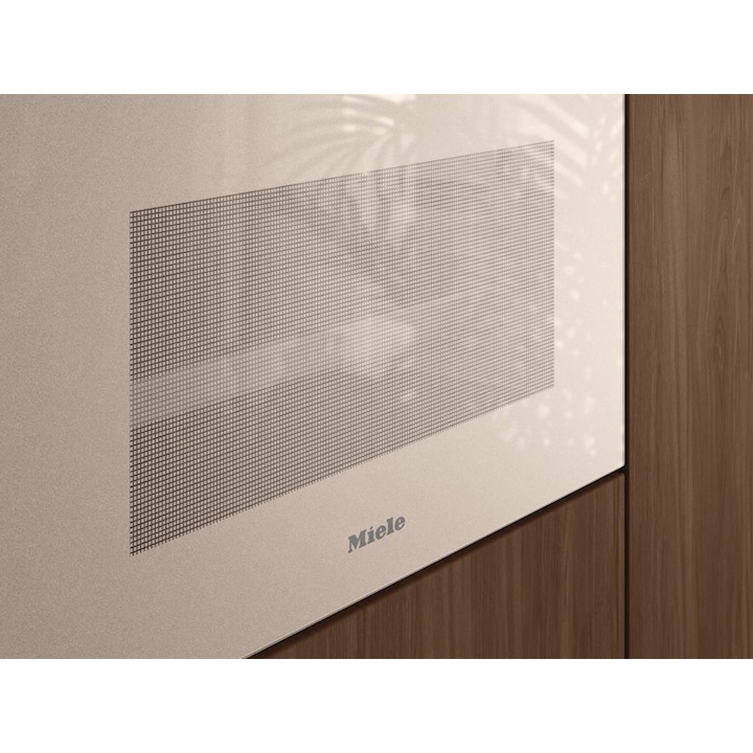 Close-up of a pearl beige speed oven with a mesh screen and Miele logo