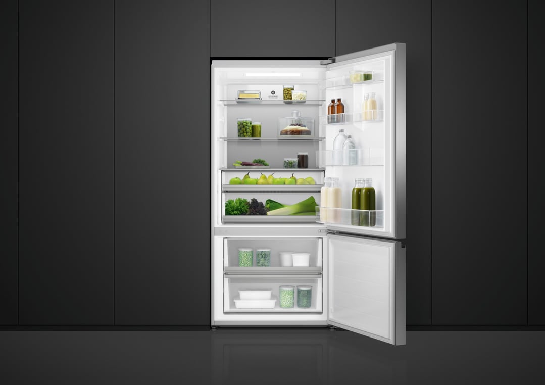 Open bottom mount fridge filled with food in a dark kitchen