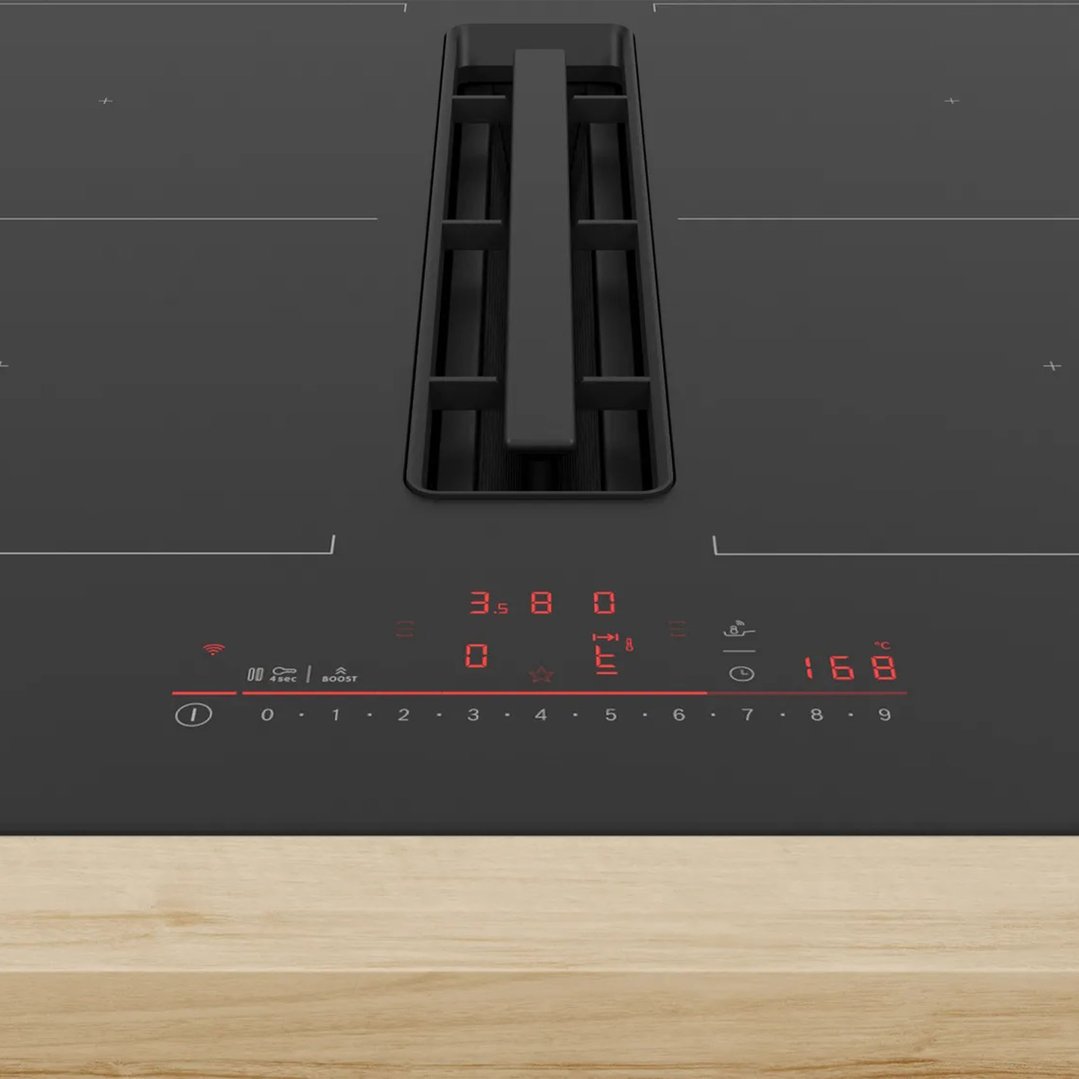 Close-up of a black cooktop with integrated ventilation on a wooden countertop