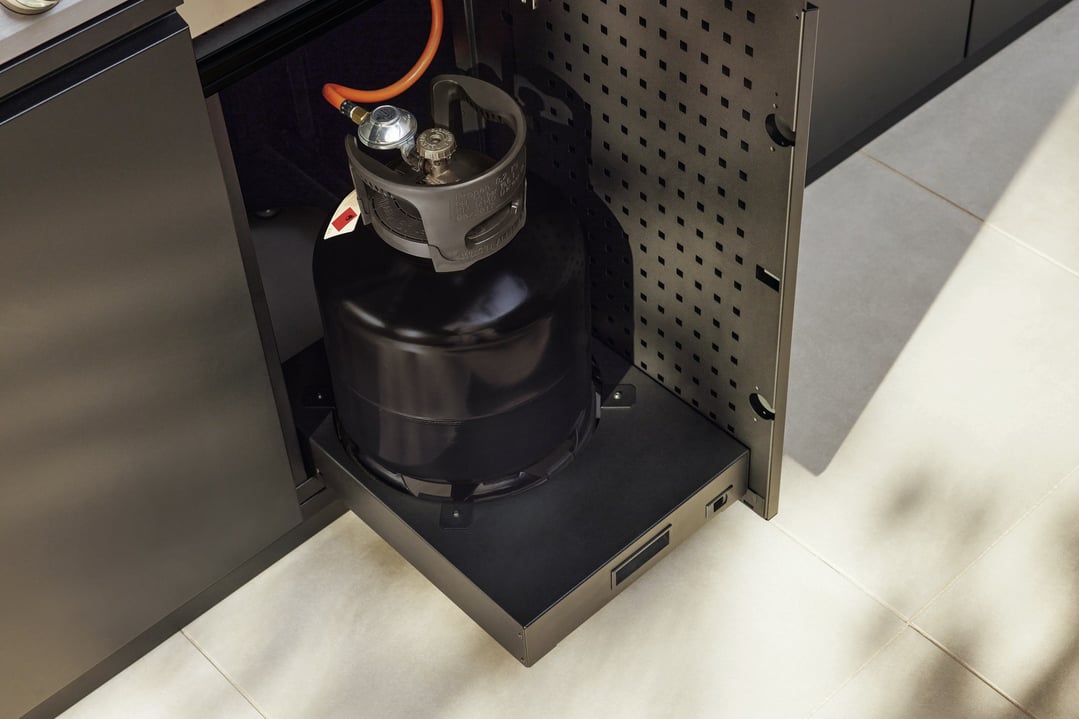 A black gas bottle on a pull-out tray inside a dark cabinet