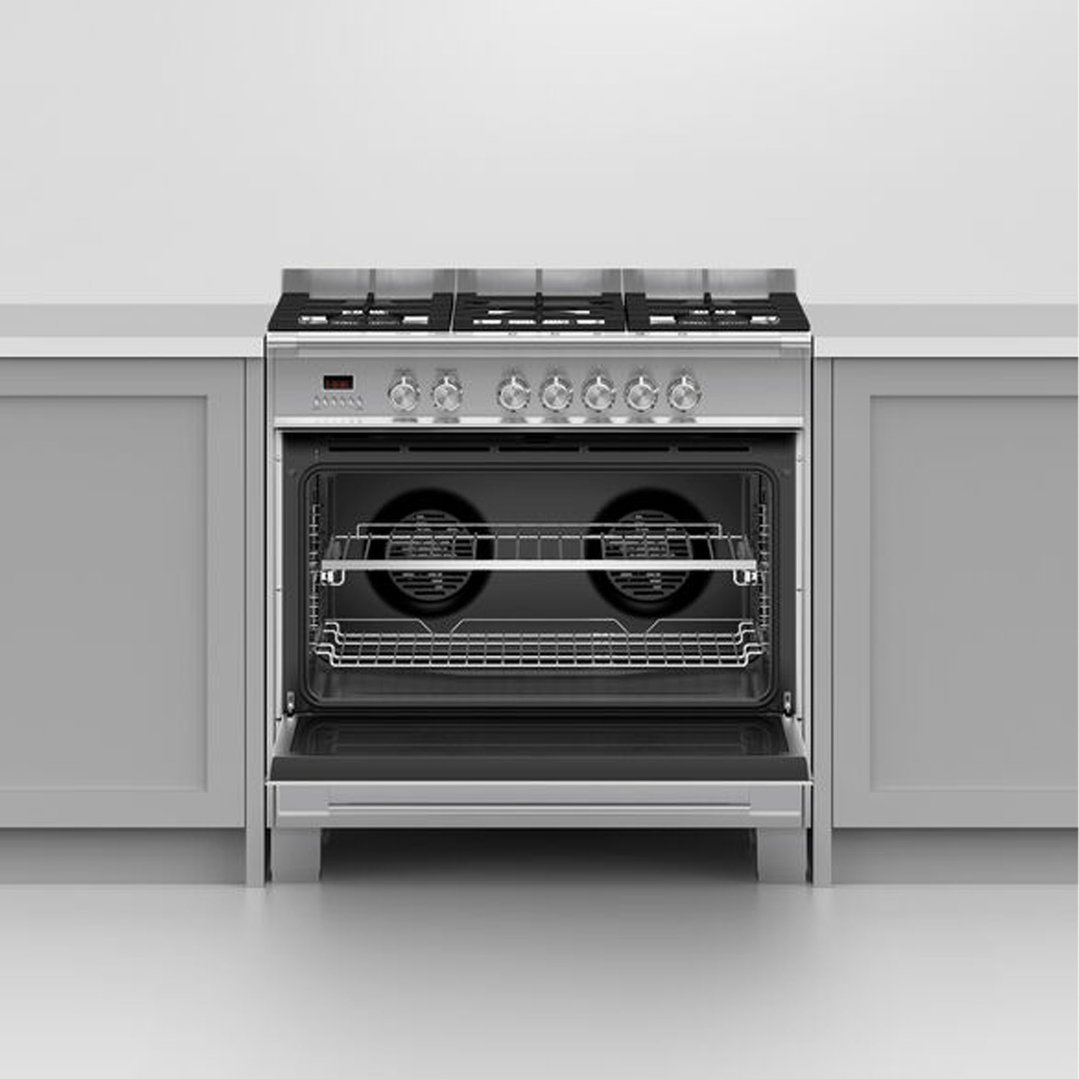 Stainless steel dual fuel cooker with open oven door in a kitchen setting