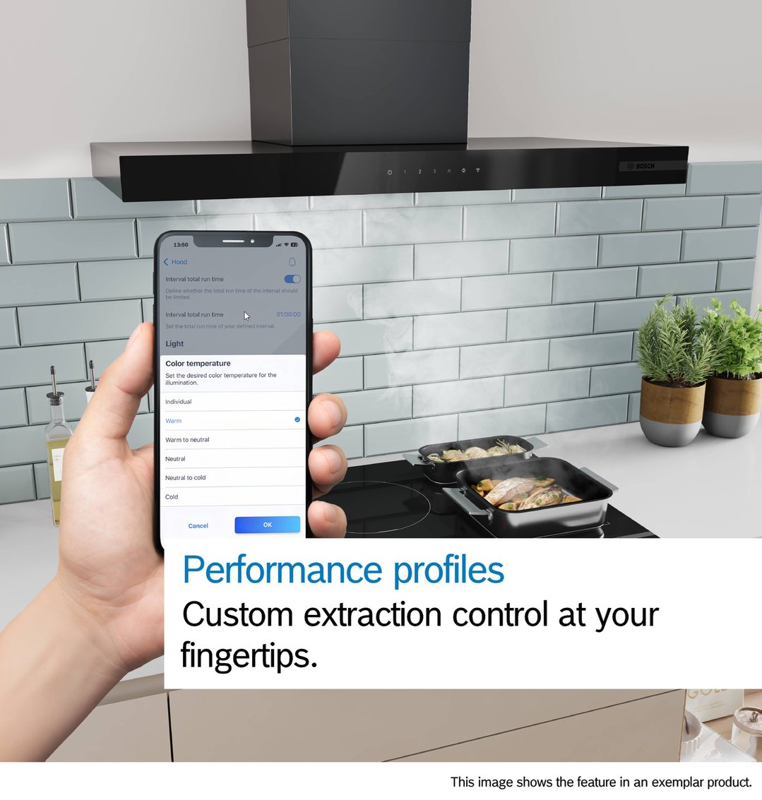 Hand holding a smartphone controlling a rangehood in a modern kitchen