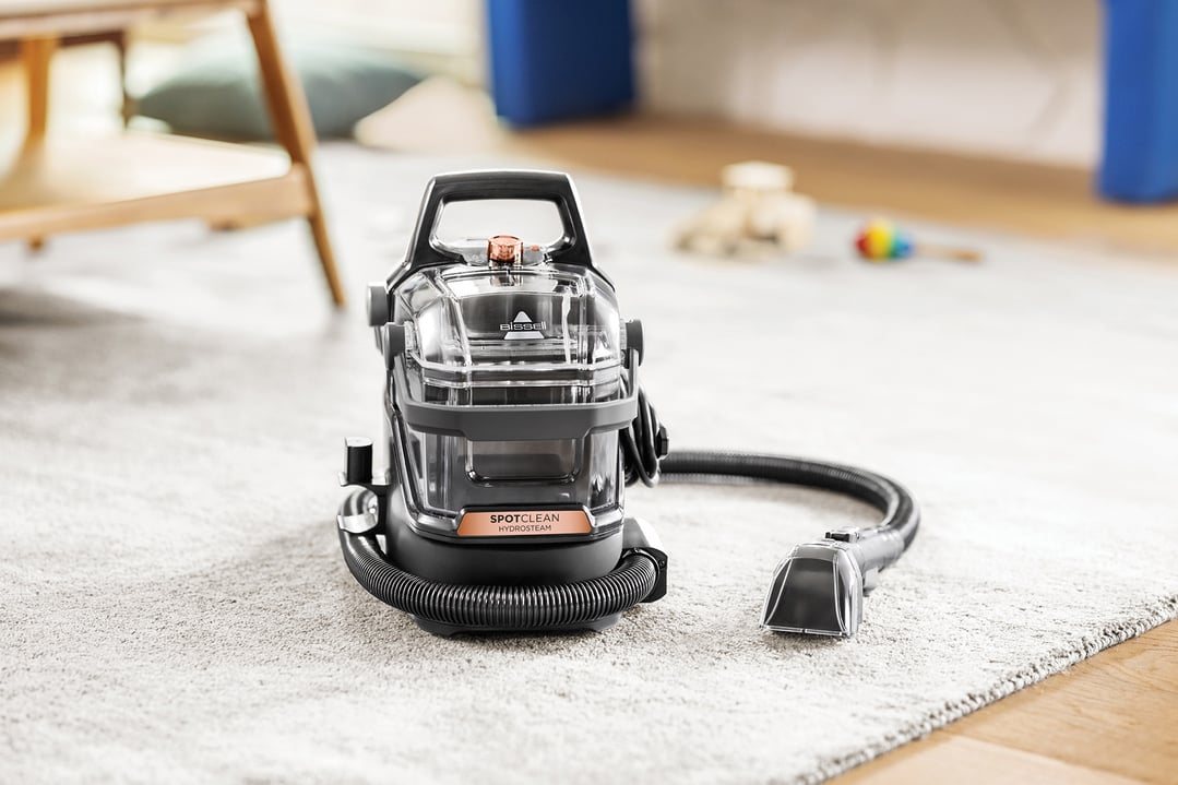 BISSELL SpotClean HydroSteam vacuum cleaner on a carpeted floor in a living room