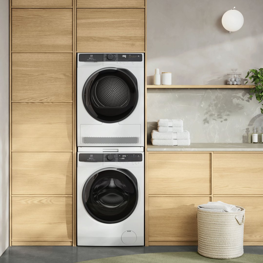 White Electrolux washing machine and dryer stacked in a modern laundry room