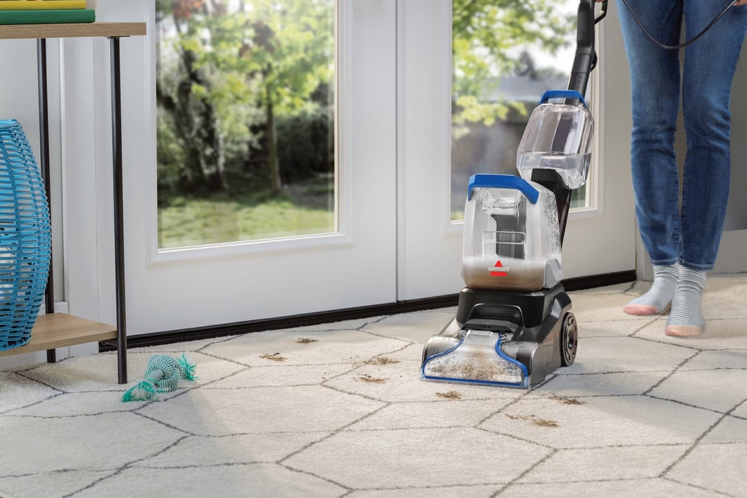 Person cleaning a dirty white rug with a BISSELL carpet cleaner