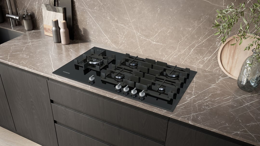 Black gas cooktop built into a marble countertop in a modern kitchen