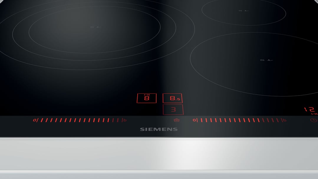 Close up of a black Siemens induction cooktop with red digital displays