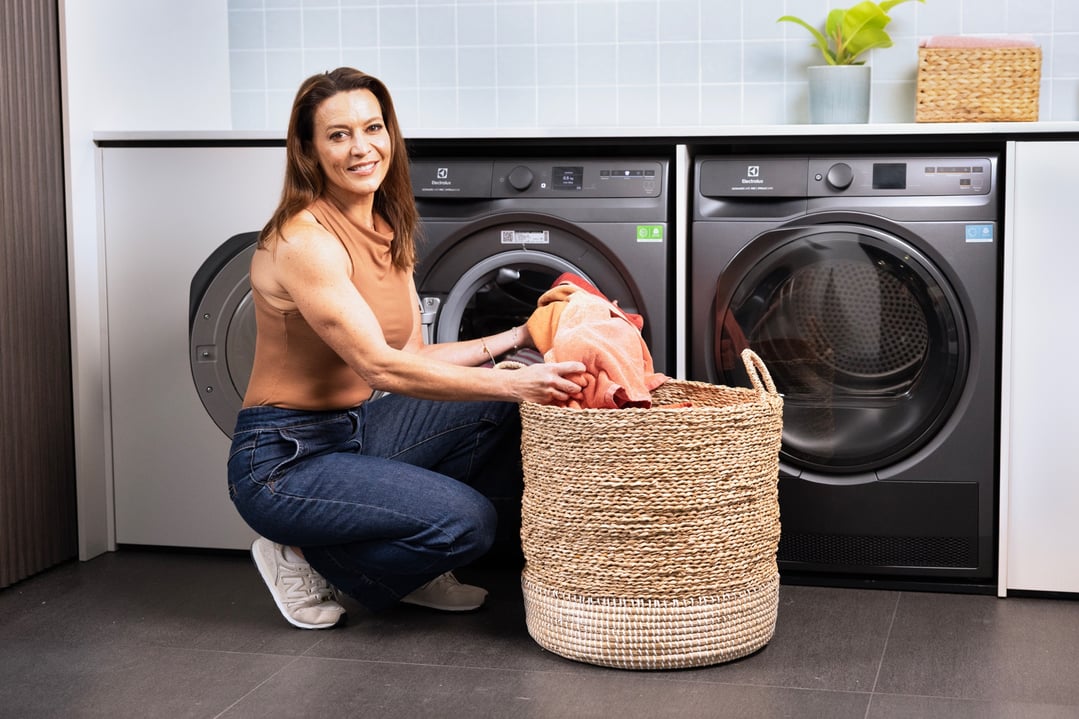 Woman loading laundry into a front-load washing machine in a modern laundry room