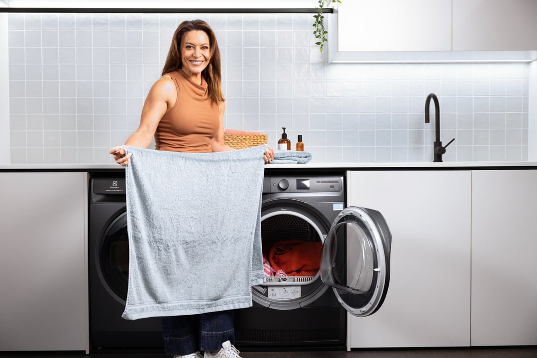 Woman holding a towel in front of a dryer in a modern laundry room