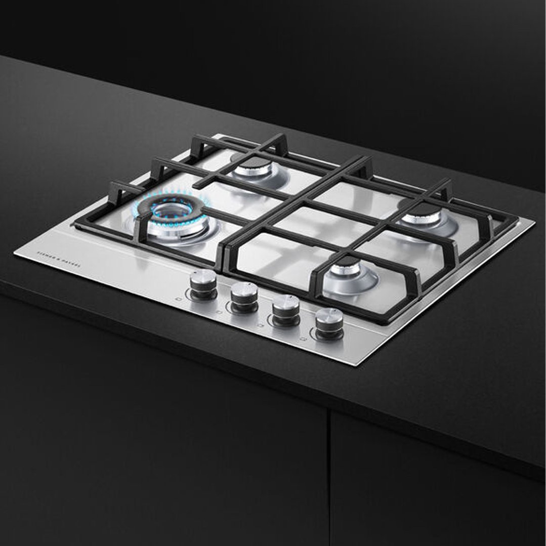 Stainless steel gas cooktop with one burner lit, built into a dark countertop