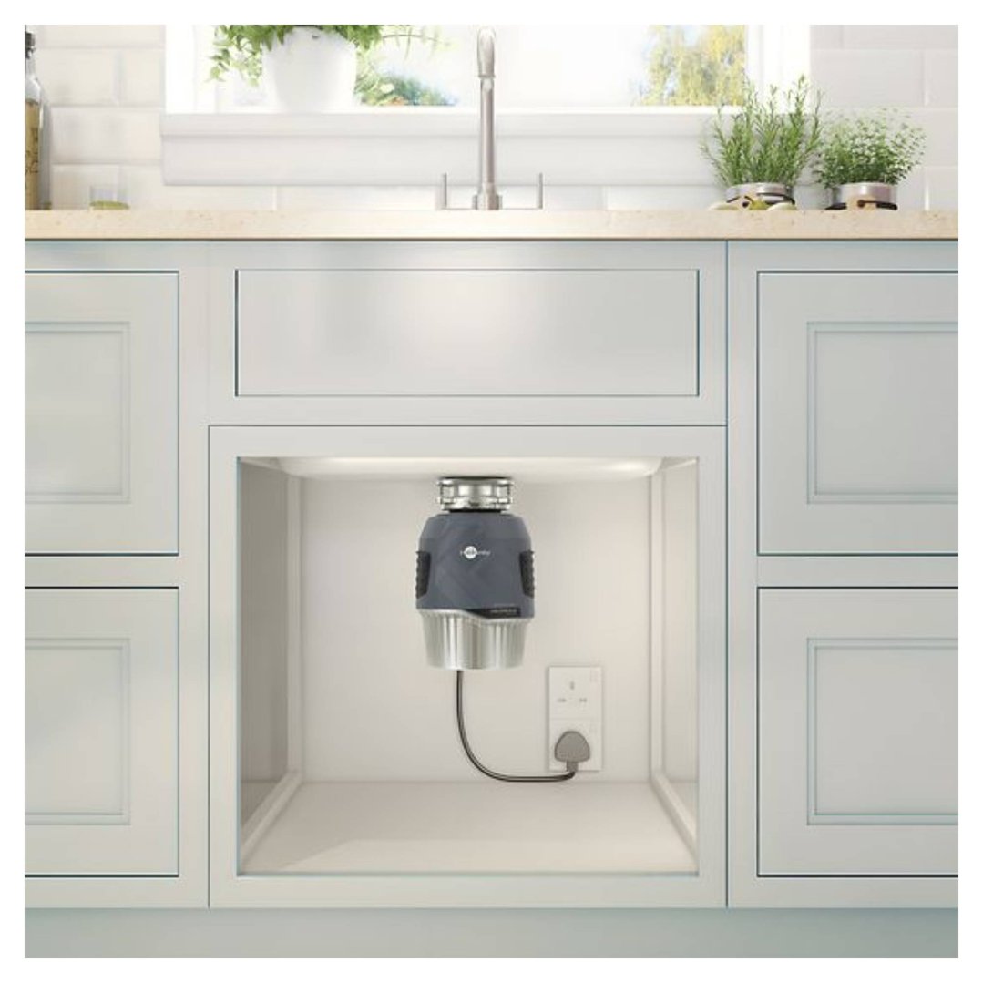 Food waste disposer installed under a kitchen sink in a white cabinet