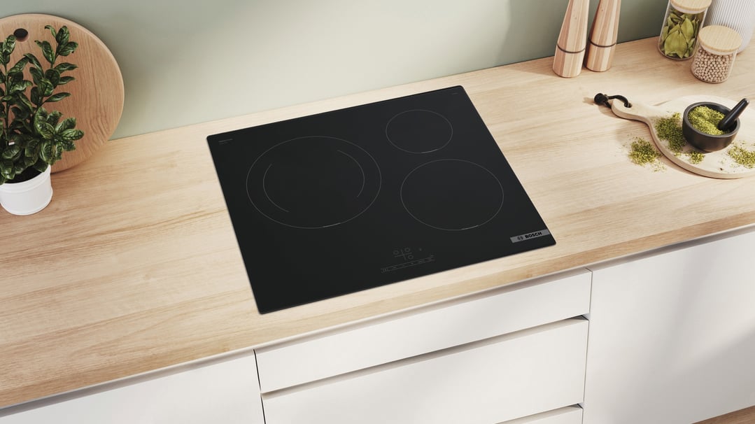 Black BOSCH induction cooktop installed in a light wood kitchen countertop