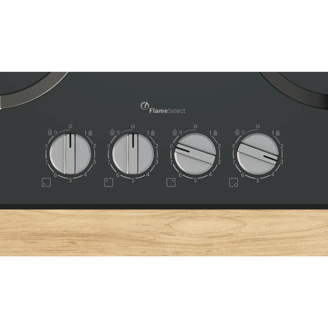 Close-up of a black gas cooktop with four control knobs on a wooden countertop