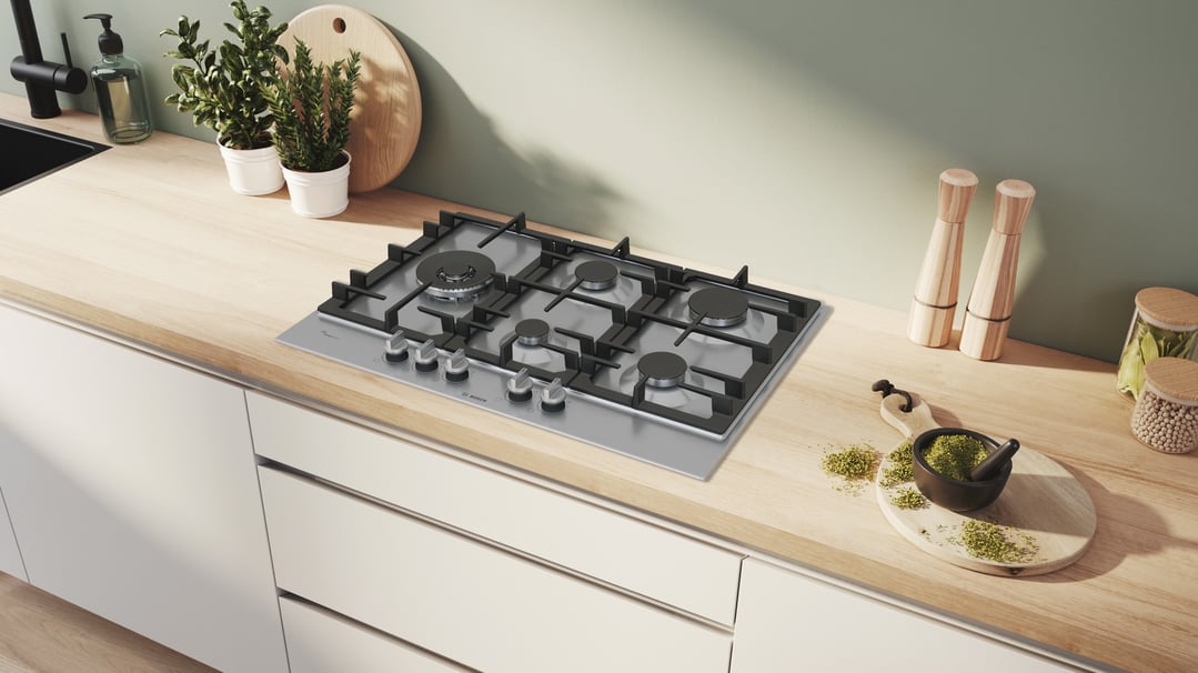 Series 6 gas cooktop built into a light wood countertop in a modern kitchen