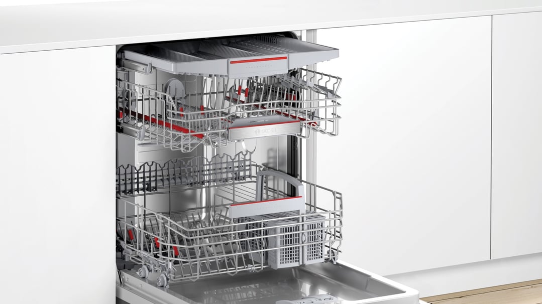 Open Bosch dishwasher with three racks in a white kitchen
