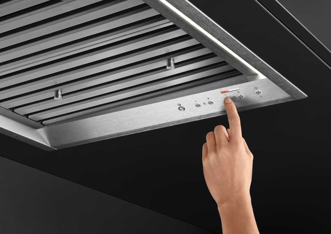 Hand adjusting controls on a Fisher & Paykel integrated insert rangehood