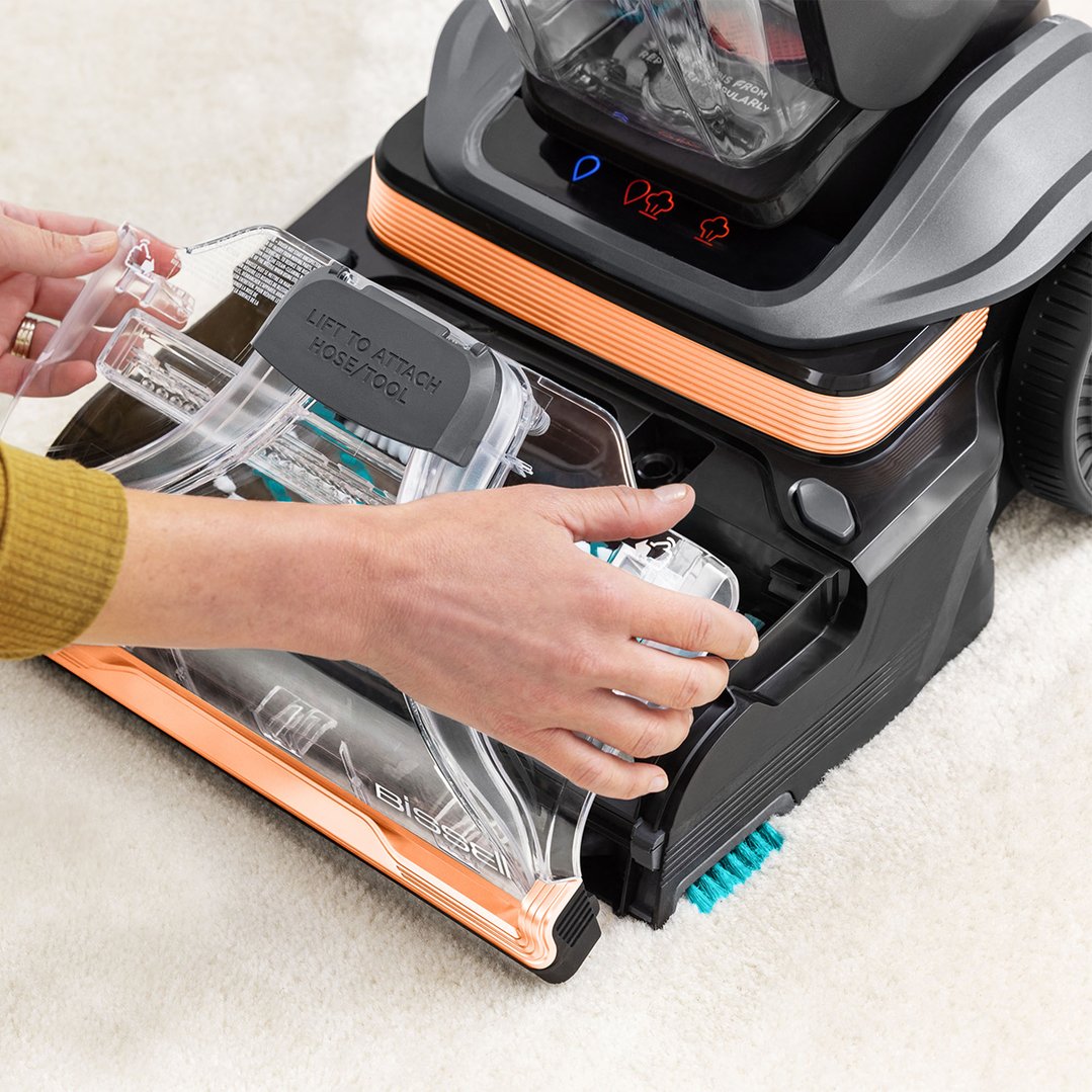 Hands attaching a clear water tank to a BISSELL vacuum cleaner