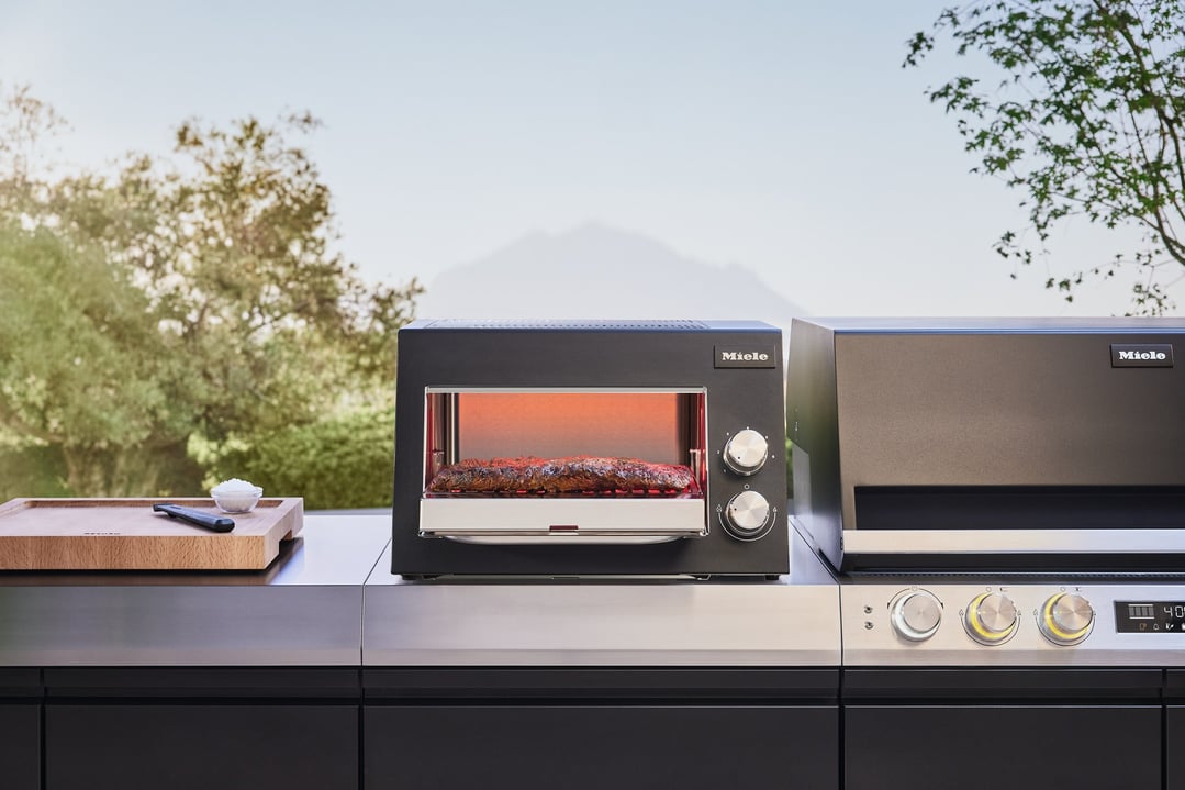 Miele Sear Pro Outdoor BBQ Sear Module cooking meat on an outdoor counter