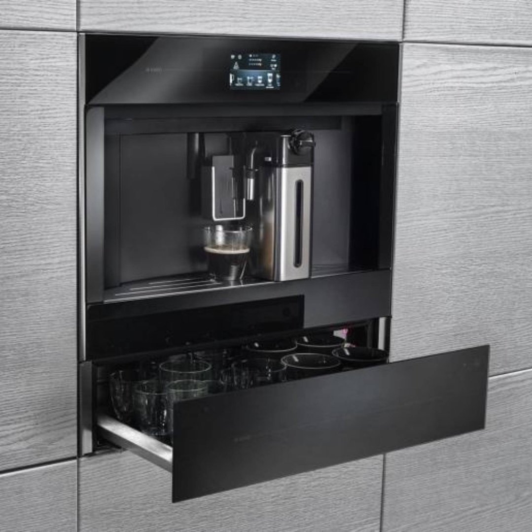 Built-in coffee machine with a glass of coffee and open drawer of cups