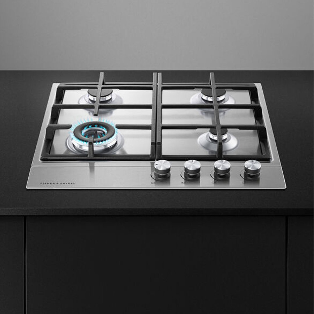 Stainless steel gas cooktop with one burner lit, built into a black countertop