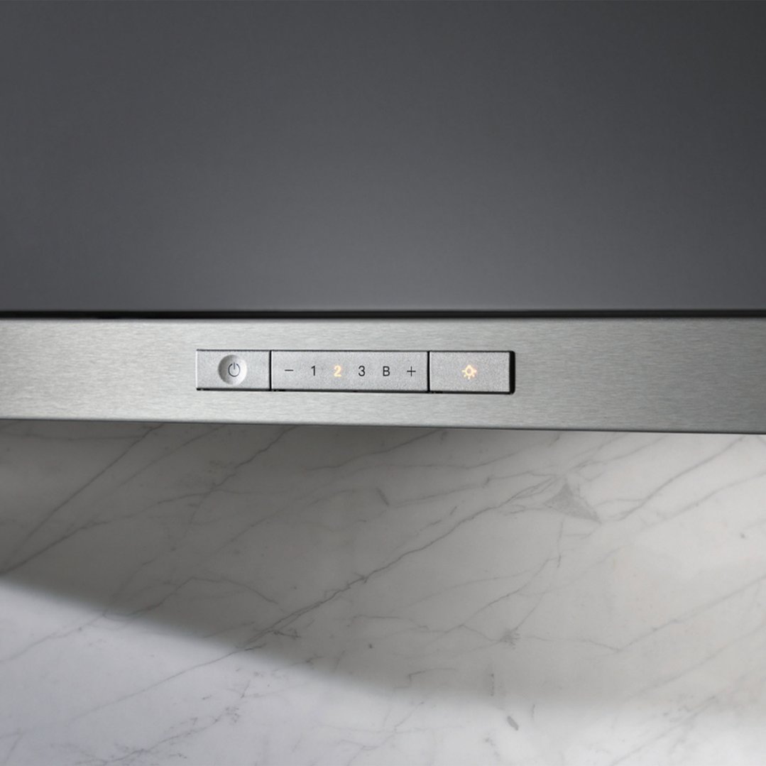 Close up of a rangehood control panel with illuminated buttons above a marble surface